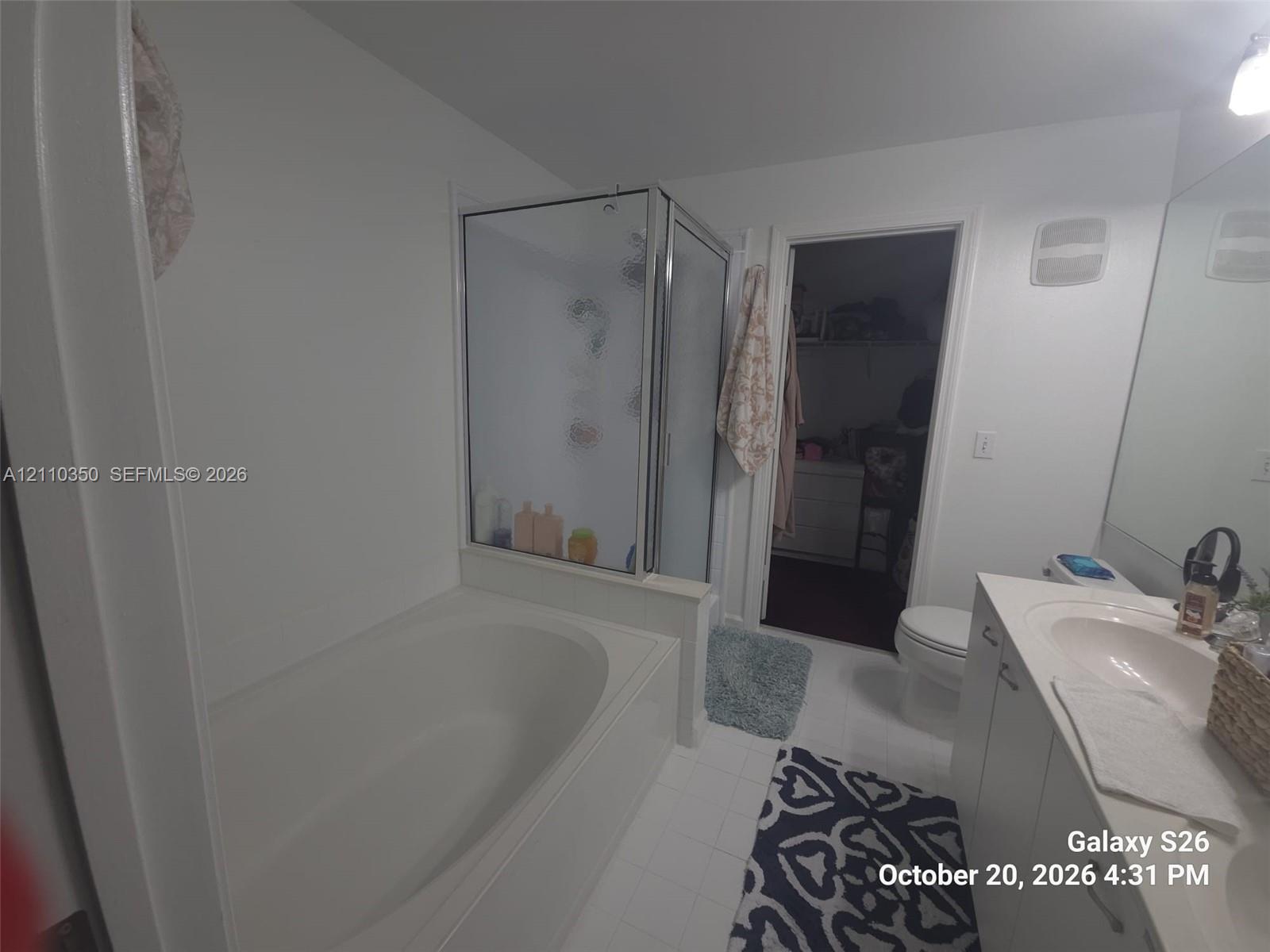 Bathroom featuring an oval soaking tub, separate glass-enclosed shower, integrated vanity with a molded sink, and wall-to-wall mirror