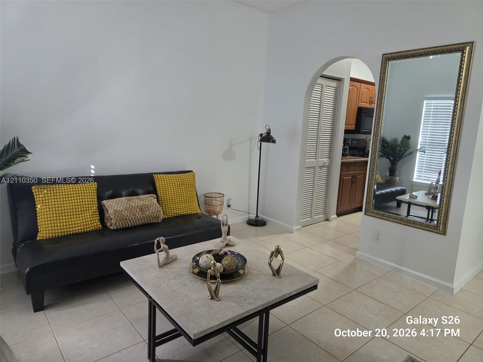 Neutral-toned ceramic tile flooring, arched wall opening, and louvered closet doors Neutral-toned ceramic tile flooring, arched wall opening, and louvered closet doors