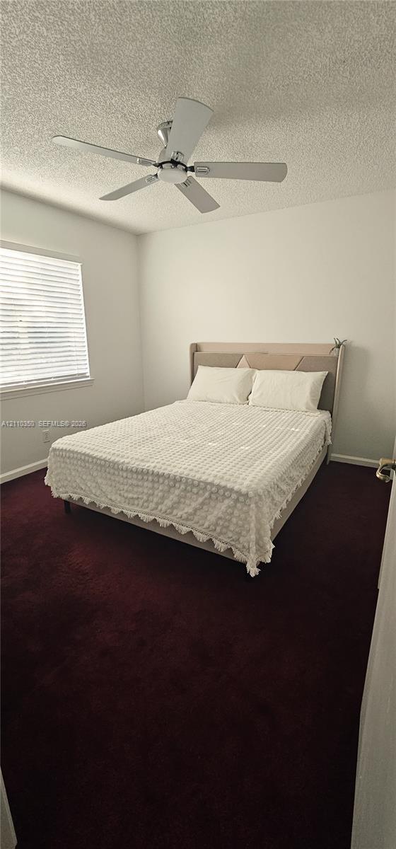 Room featuring deep-toned carpet flooring, a ceiling fan with integrated lighting, and a window with horizontal blinds