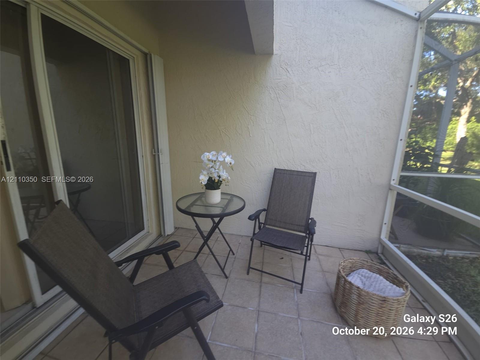 Screened-in patio with light-toned tiled flooring and sliding glass door entry