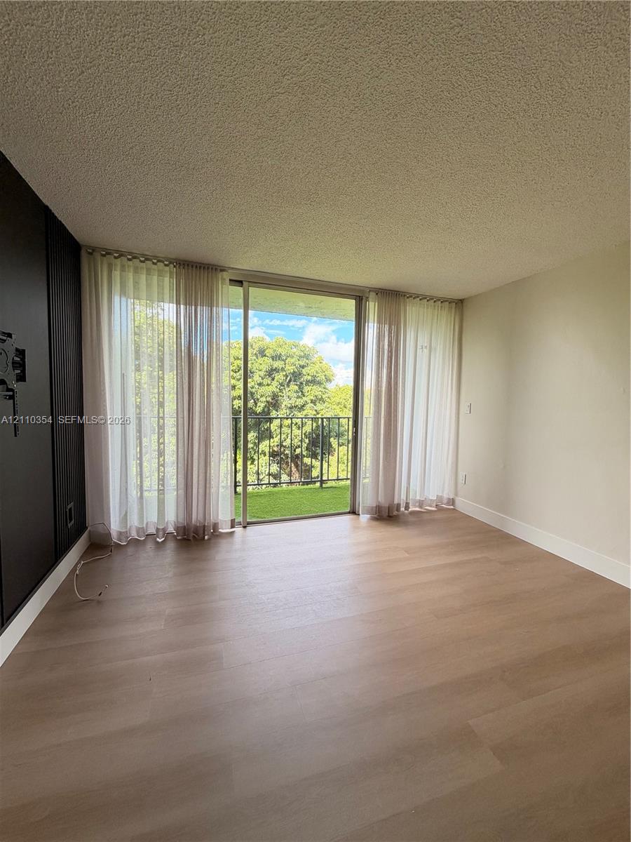 Wood-finish flooring, floor-to-ceiling sliding glass doors, and a private balcony featuring a metal railing