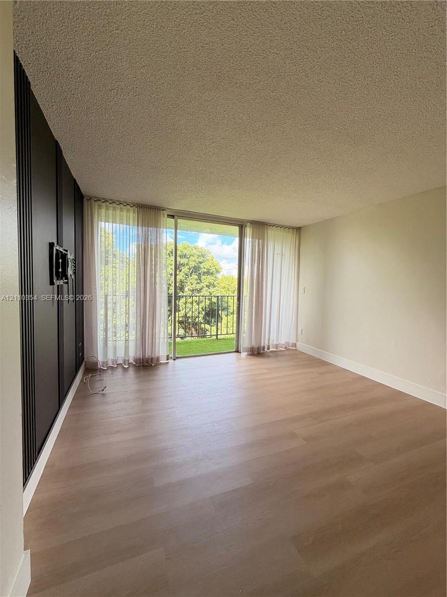 Wood-finish flooring, floor-to-ceiling sliding glass doors, decorative dark vertical paneling, and a metal-railed exterior balcony