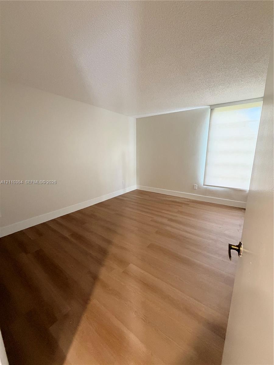 Room featuring neutral wall finishes, wood-finish flooring, and a window with a retractable shade
