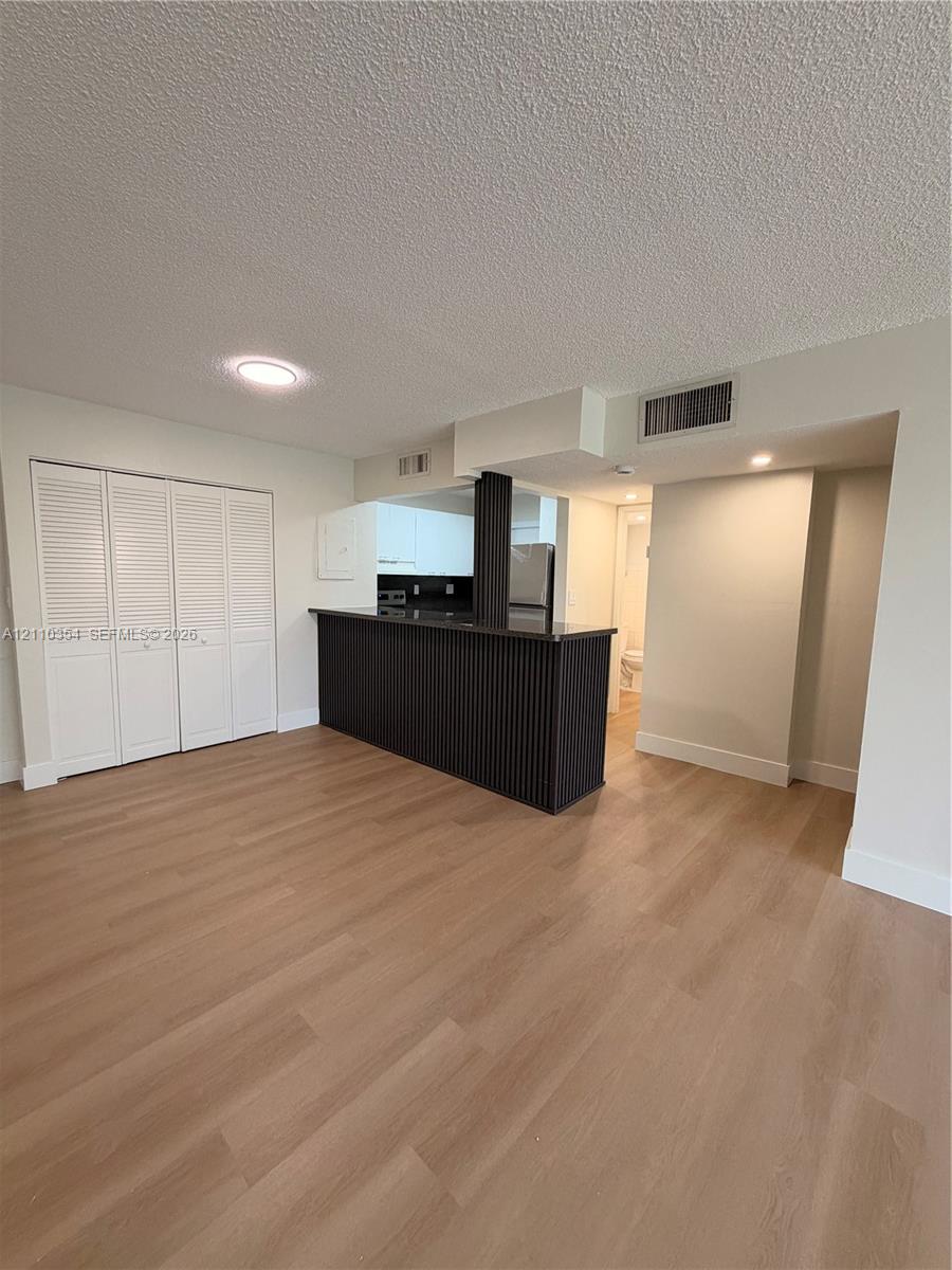 Wood-finish flooring, white louvered-door closet, and dark-toned breakfast bar featuring fluted cabinetry detailing
