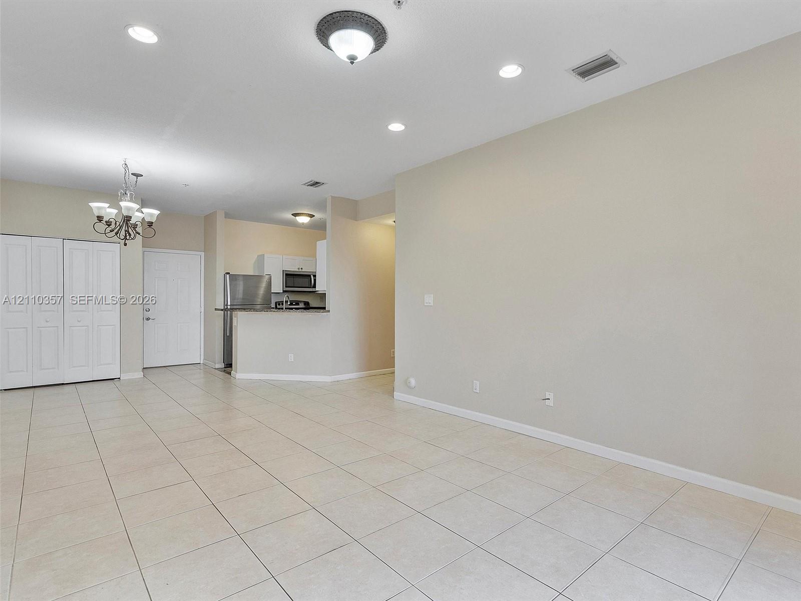 Interior space featuring neutral tile flooring, recessed lighting, a multi-light chandelier, and built-in closet cabinetry
