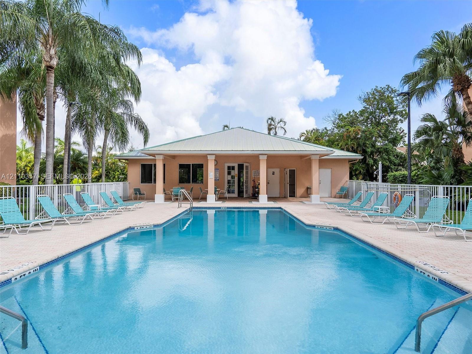 Swimming pool with tile edging, concrete pool deck, covered pavilion, and perimeter fencing