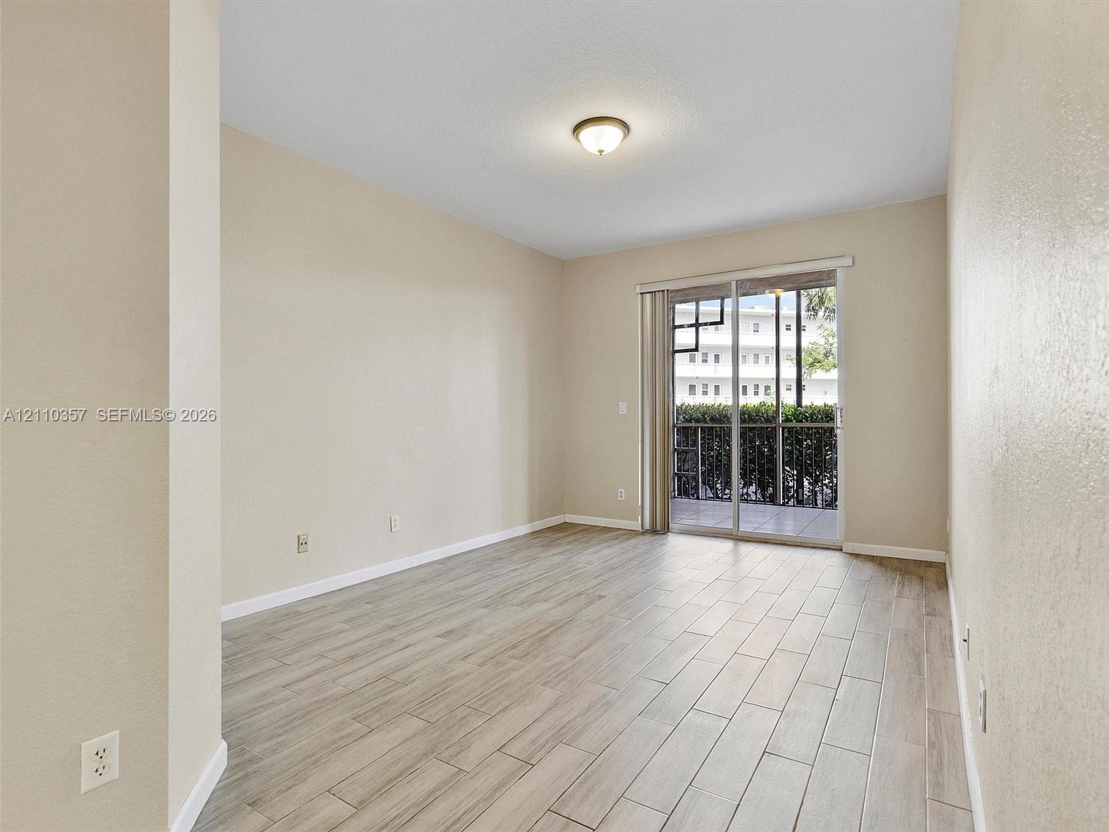 Interior space featuring neutral wall paint, wood-finish tile flooring, a flush-mount ceiling light fixture, and sliding glass doors