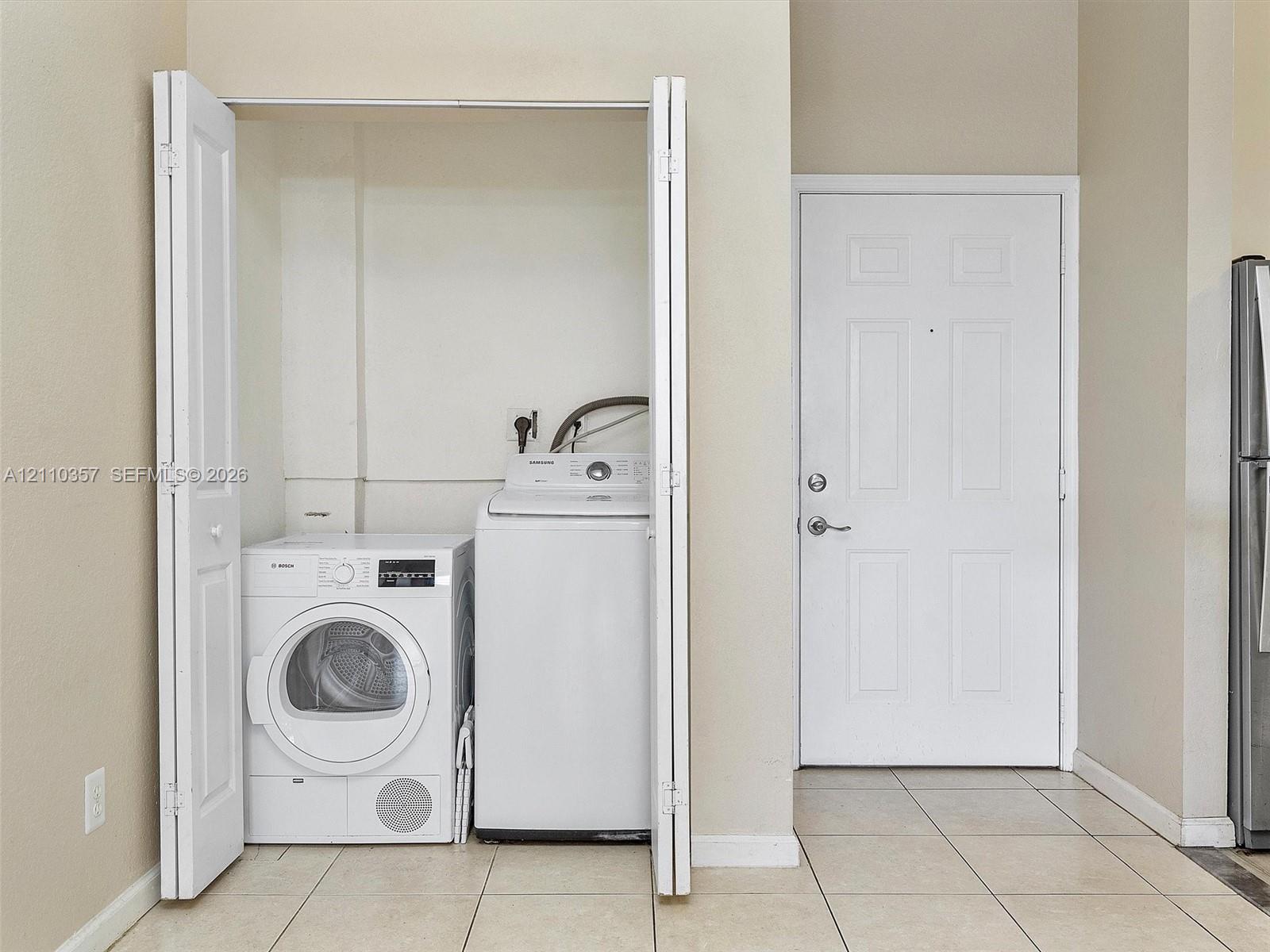 Laundry closet with folding bifold doors and tile flooring