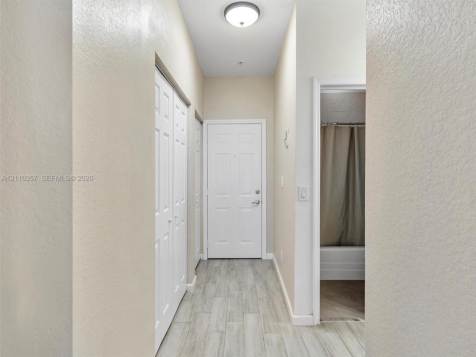 Entryway featuring wood-finish tile flooring, recessed ceiling lighting, and multi-panel interior doors