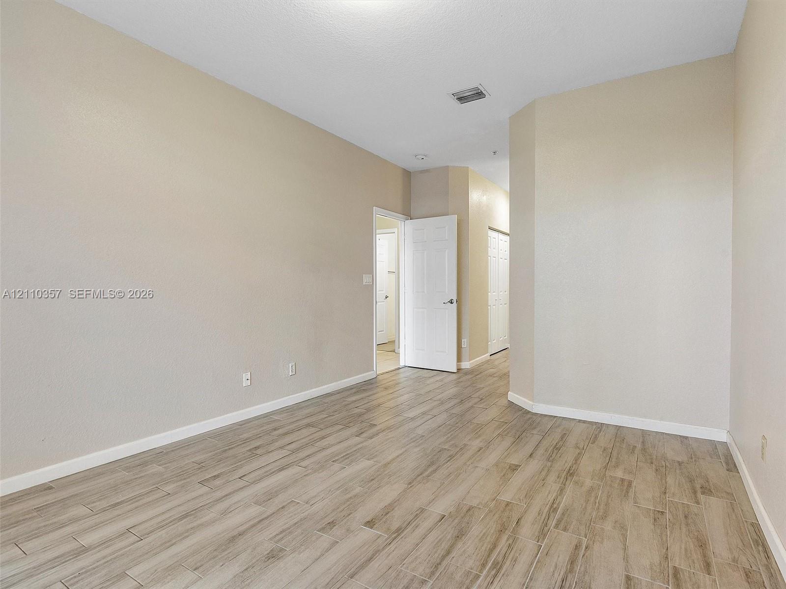 Interior space featuring neutral wall paint, wood-finish flooring, and multiple white interior doors