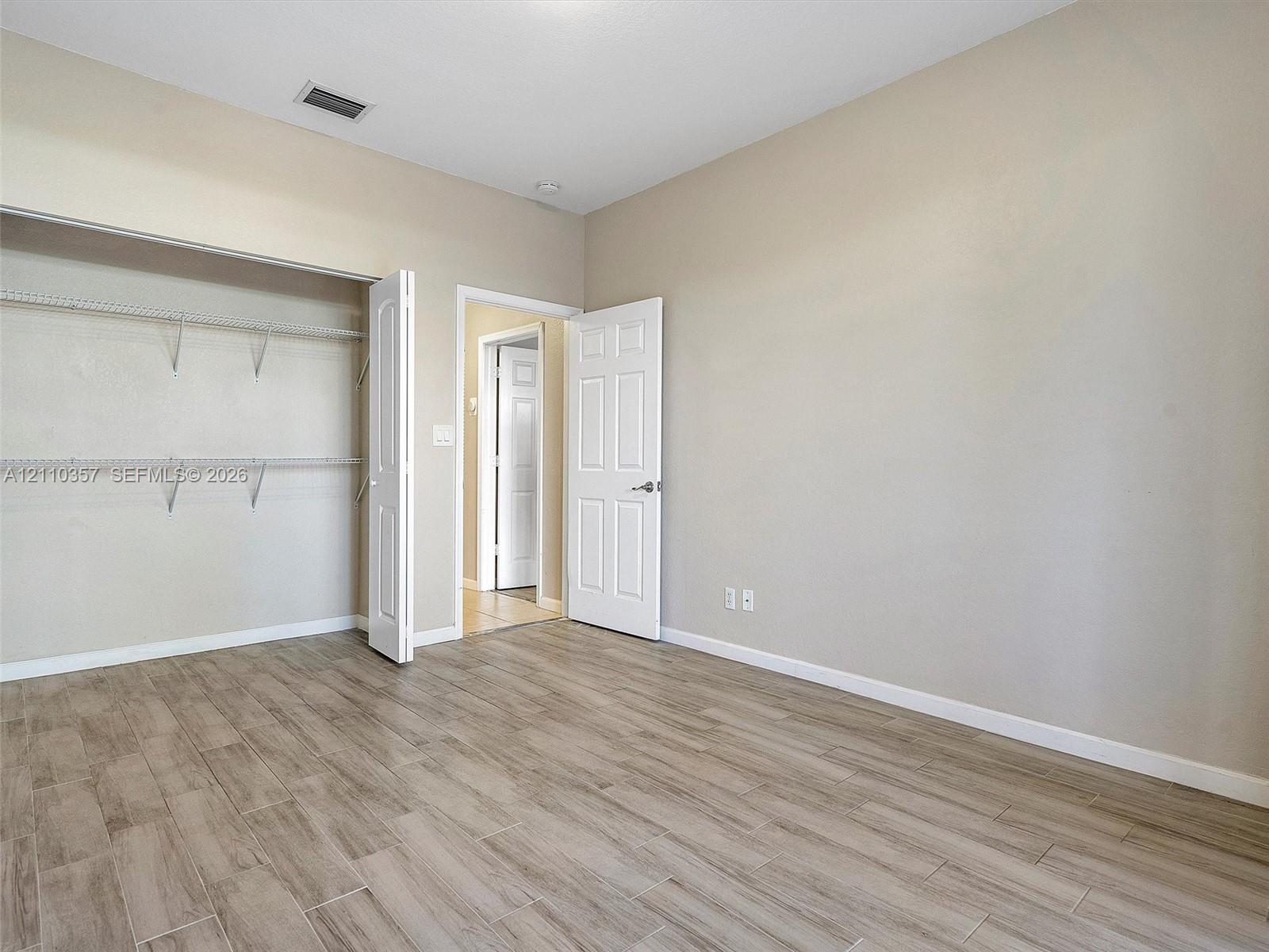 Room featuring wood-finish flooring, neutral wall paint, and a built-in closet with wire shelving