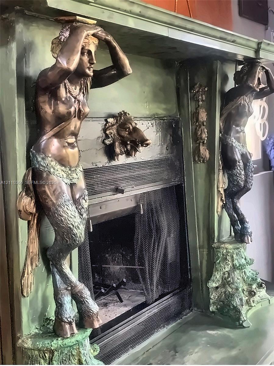 Fireplace surround featuring dual metallic caryatid supports, ornate figural wood-finish detailing, and a central animal motif relief