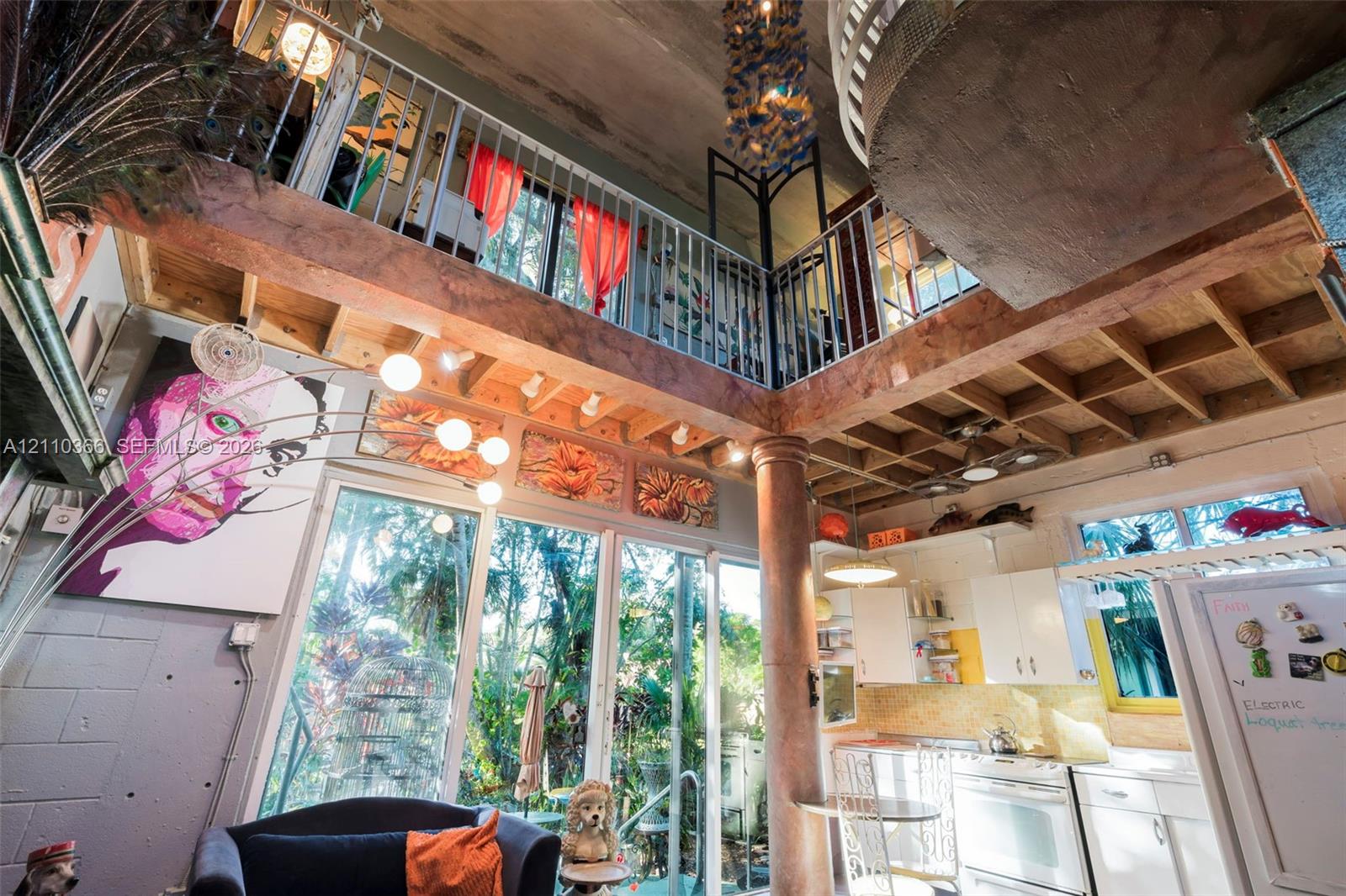 Exposed timber joist ceilings with double-height volume, central decorative column, interior metal-railed mezzanine, and floor-to-ceiling glass panel windows