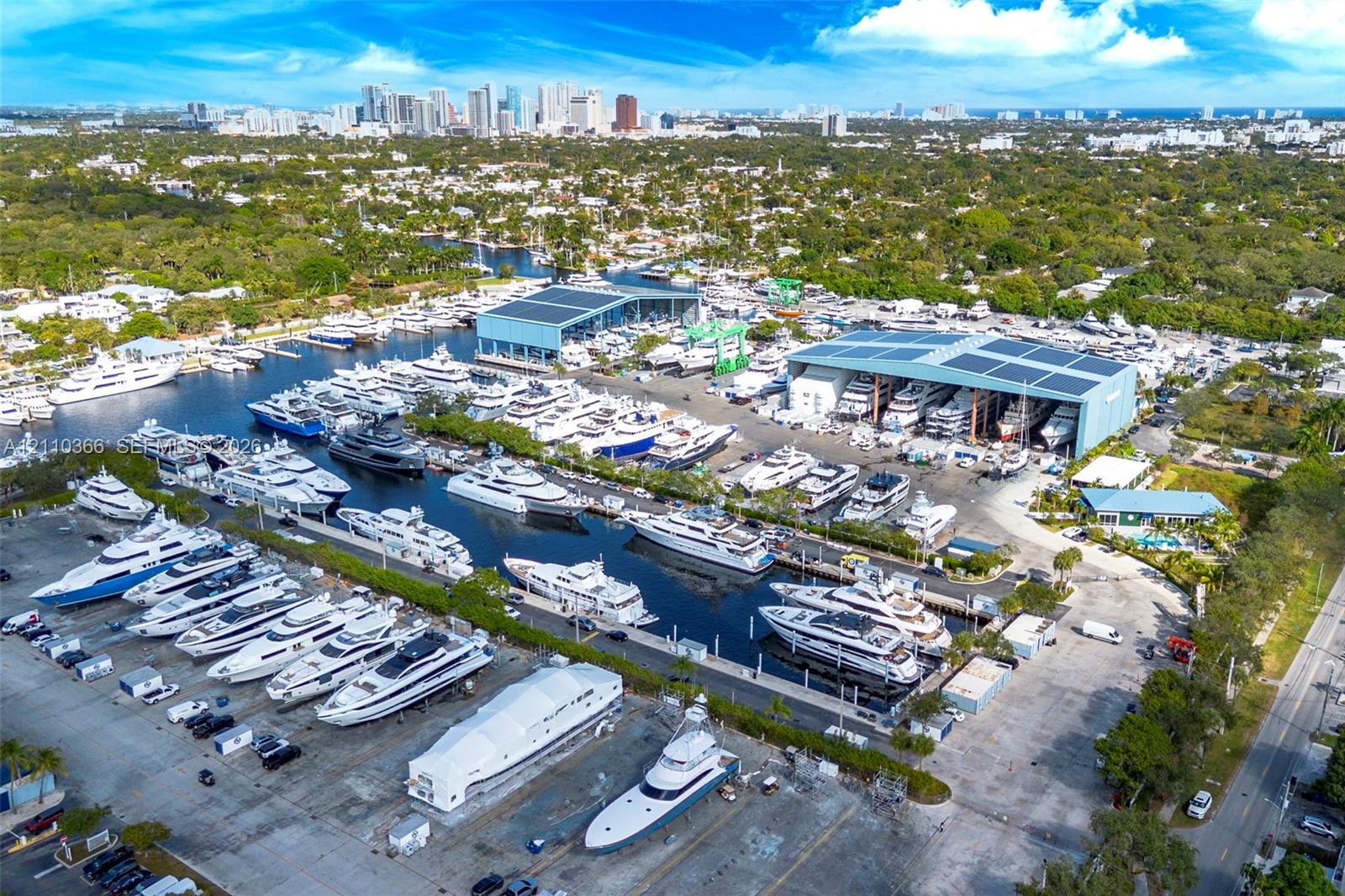Aerial perspective of a marina featuring extensive deep-water dockage, multiple climate-controlled boat storage hangars, paved hardstanding areas, and direct waterfront access