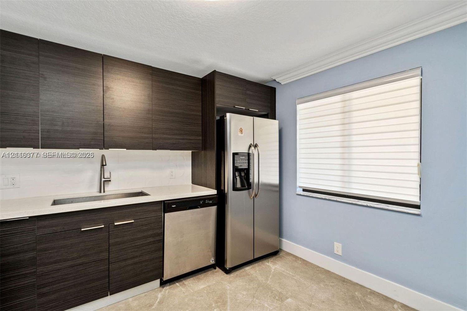 Kitchen featuring dark wood-finish cabinetry, light-colored countertops, stainless steel appliances, a single-basin sink with a gooseneck faucet, and tile flooring