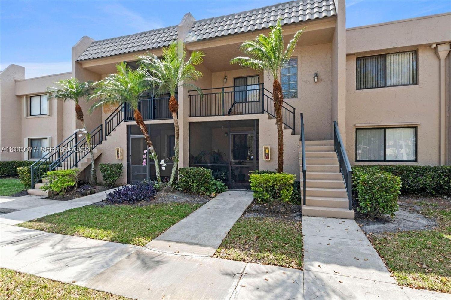 Stucco exterior featuring tile roof accents, ground-level screened-in patios, a second-story balcony with metal railings, and exterior staircase access