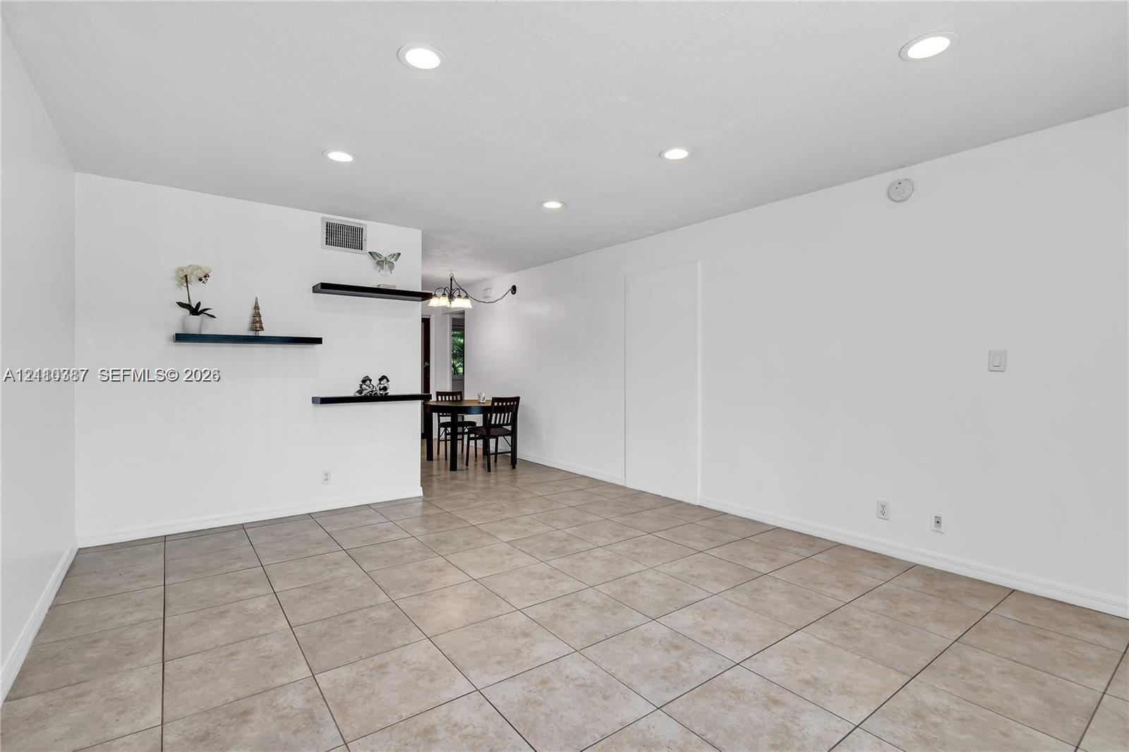 Neutral-toned tile flooring, recessed ceiling lighting, and three built-in wall-mounted display shelves Neutral-toned tile flooring, recessed ceiling lighting, and three built-in wall-mounted display shelves