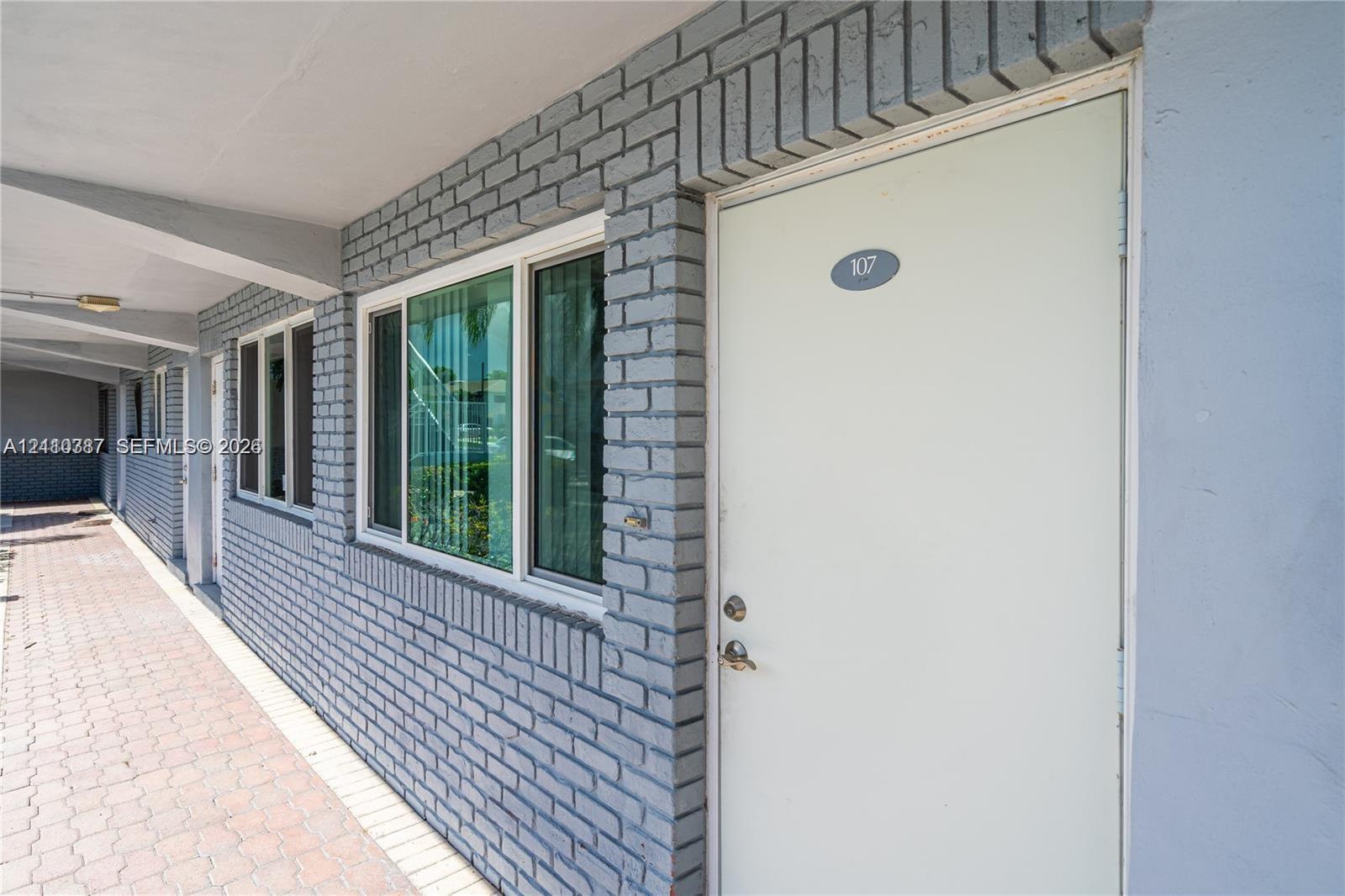 Painted brick exterior facade featuring multi-pane windows and a paved walkway