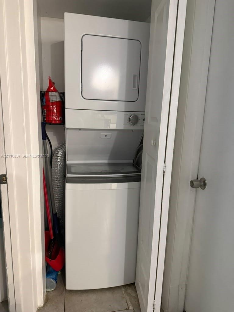 Stacked laundry unit featuring a white top-loading washer and integrated electric dryer Stacked laundry unit featuring a white top-loading washer and integrated electric dryer