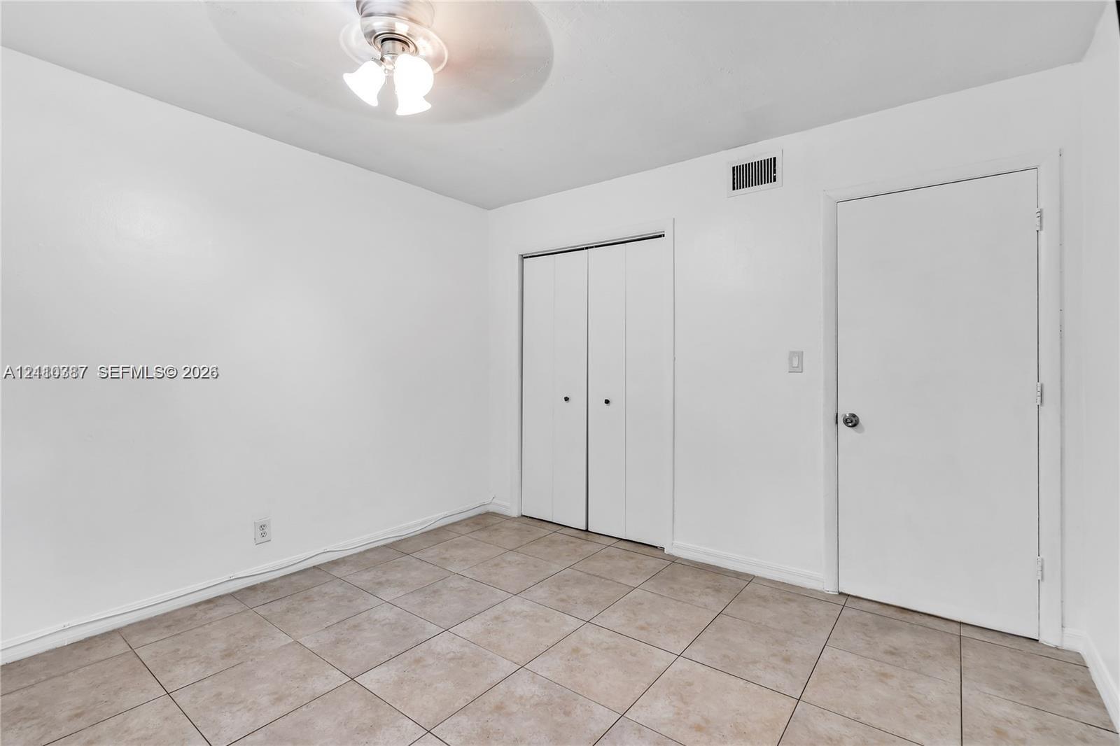 Neutral-toned tile flooring, white interior walls, ceiling-mounted light fixture, and closet with bifold doors Neutral-toned tile flooring, white interior walls, ceiling-mounted light fixture, and closet with bifold doors