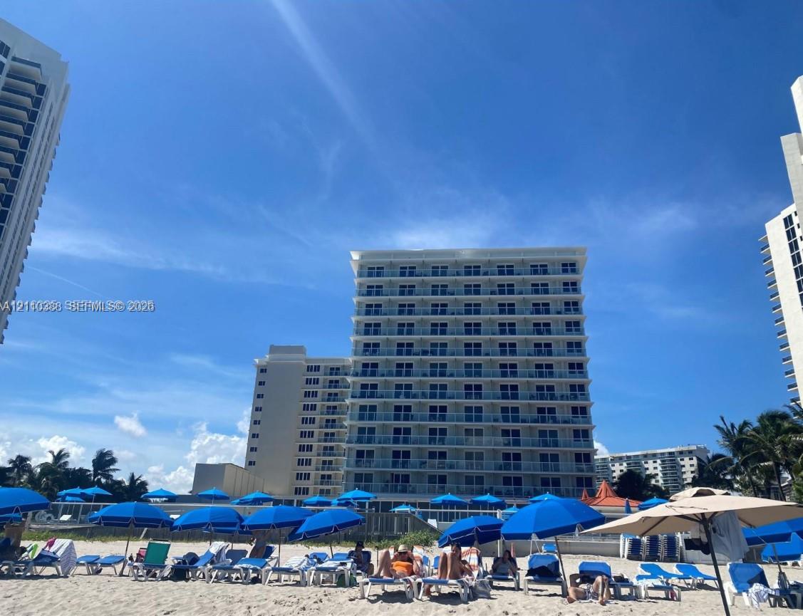 High-rise residential exterior featuring expansive glass balcony railings and direct beach access