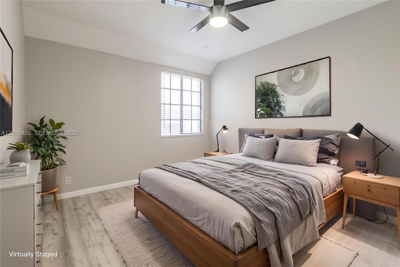 Neutral-toned interior space featuring wood-finish flooring, a multi-pane window, and a modern ceiling fan with integrated lighting