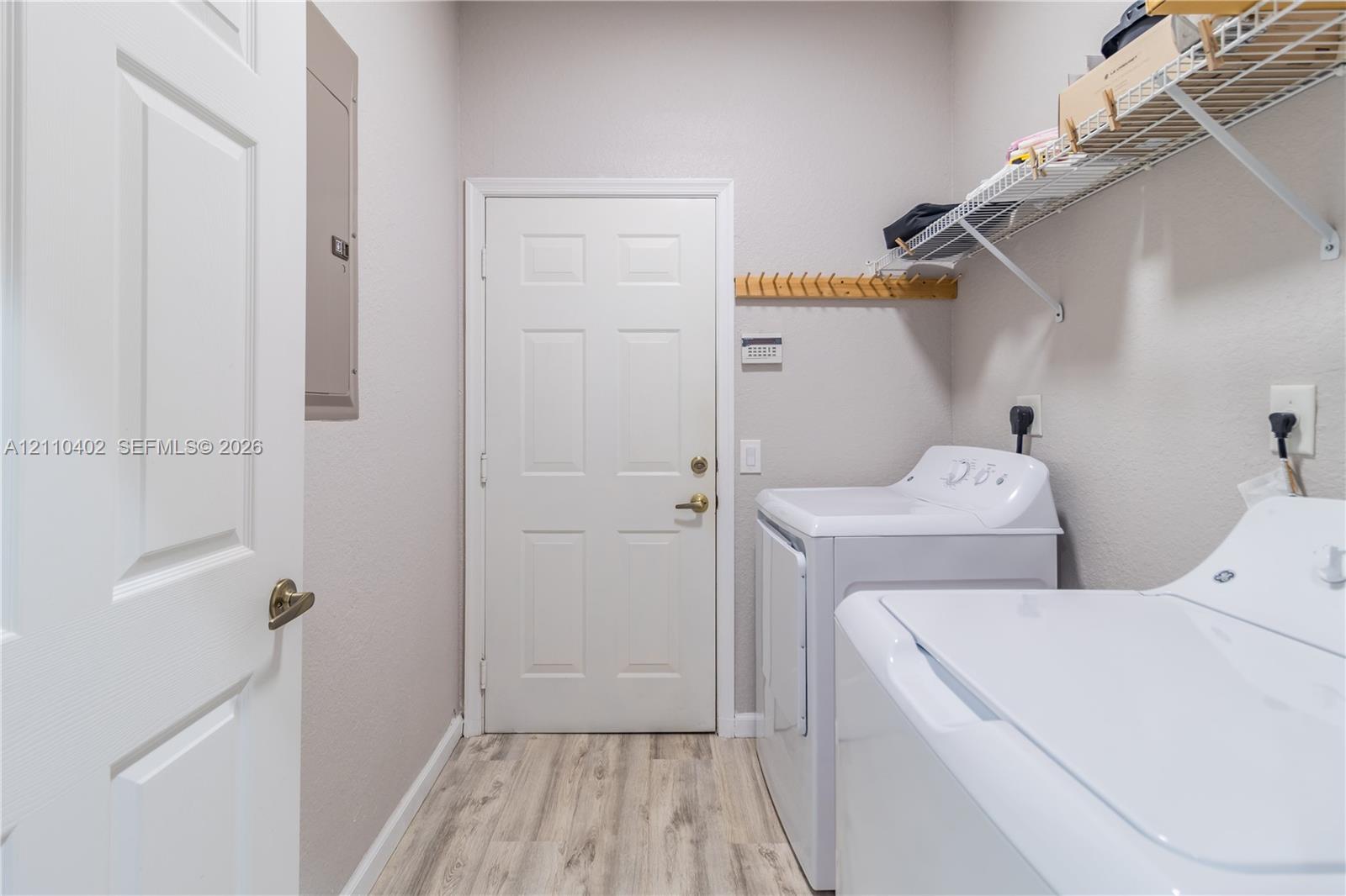 Laundry area featuring wood-finish flooring, wire shelving, and a wall-mounted wooden peg rail