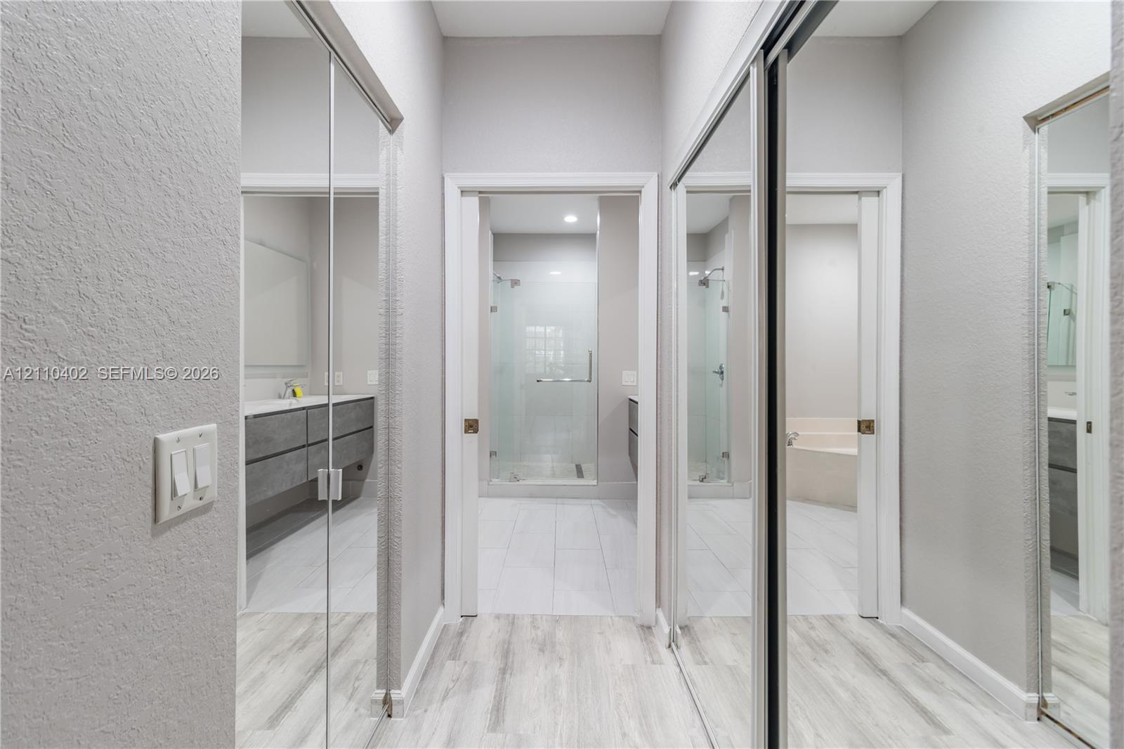 Hallway featuring full-length mirrored sliding closet doors, wood-finish flooring, and recessed lighting