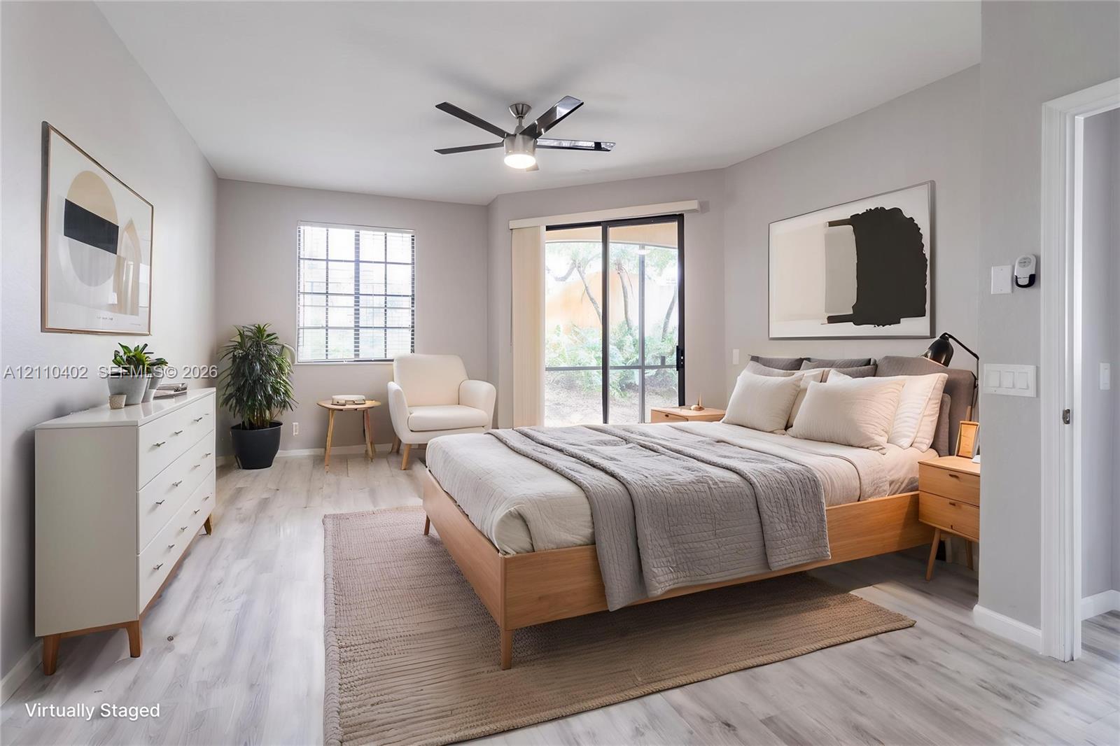 Light-toned wood-finish flooring, sliding glass door, multi-blade ceiling fan with integrated lighting, and grid-pattern window