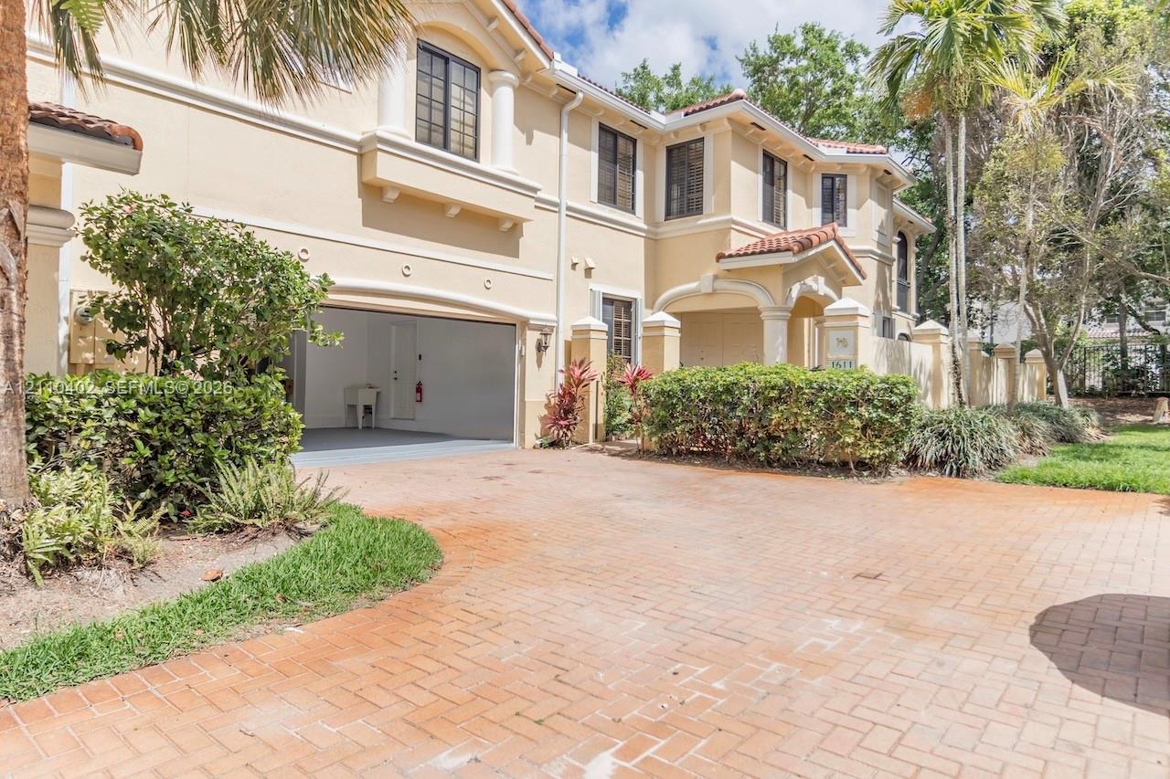Stucco exterior featuring arched architectural detailing, a paved driveway, and an integrated garage
