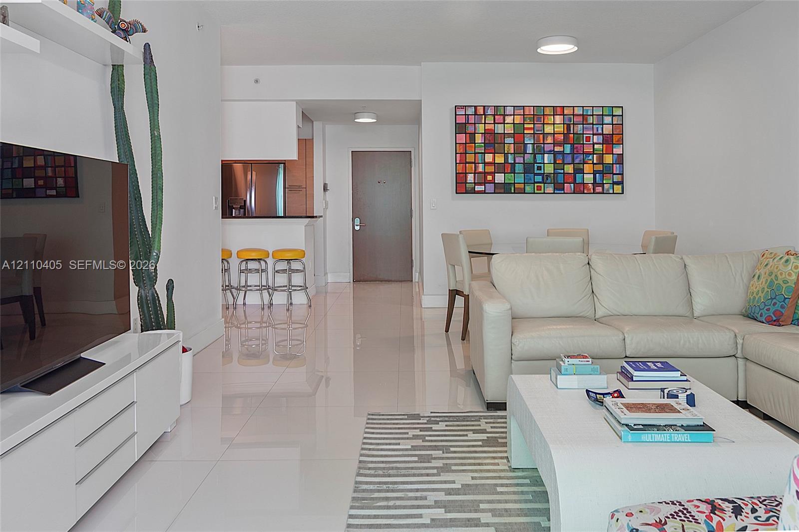 Glossy tile flooring, built-in wall-mounted media console, and kitchen breakfast bar with overhead recessed lighting