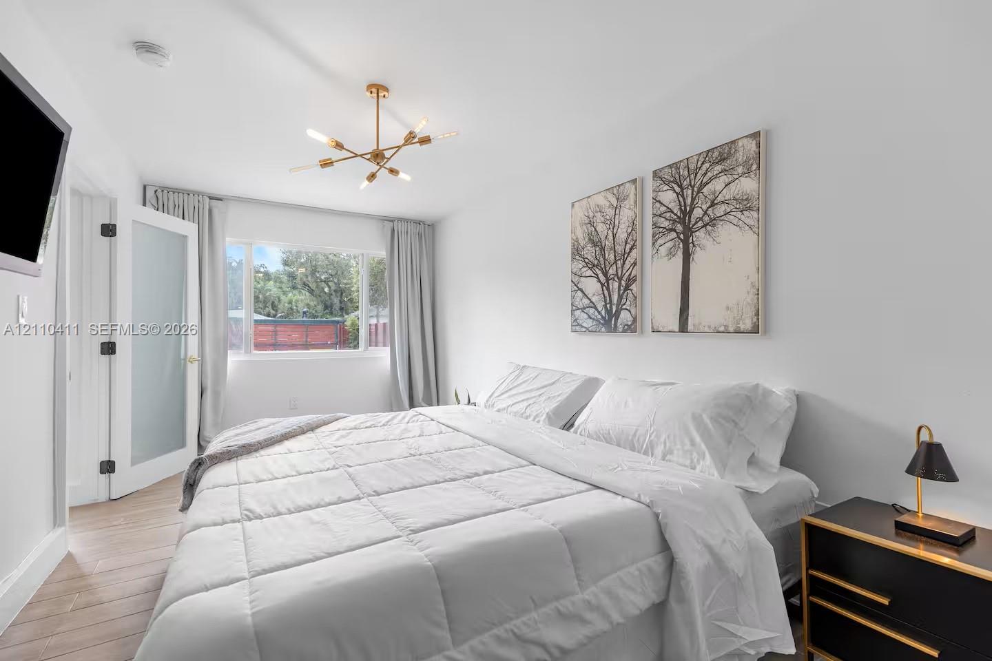 Wood-finish flooring, multi-arm gold-tone chandelier, and interior door with frosted glass panel