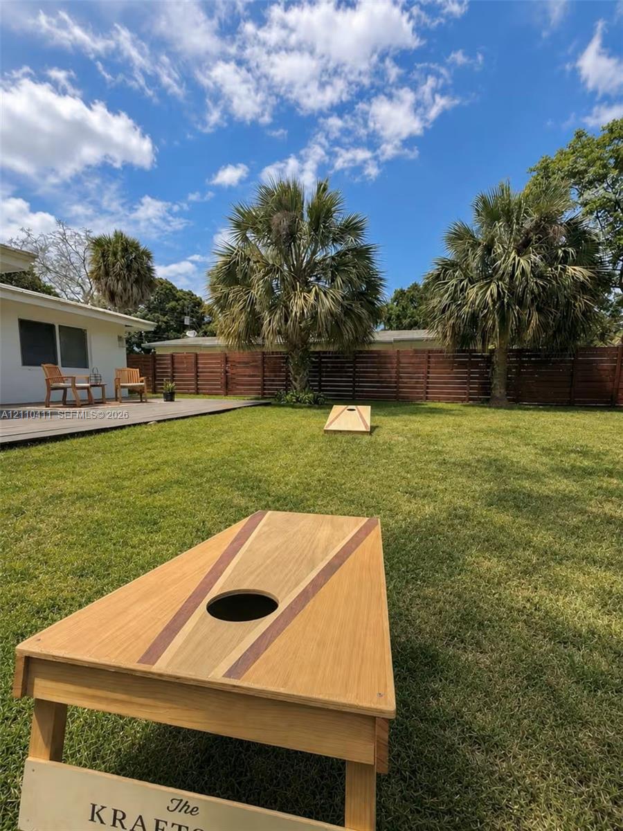 Expansive backyard featuring a leveled grass lawn, wood-finish horizontal privacy fencing, and a raised wooden deck