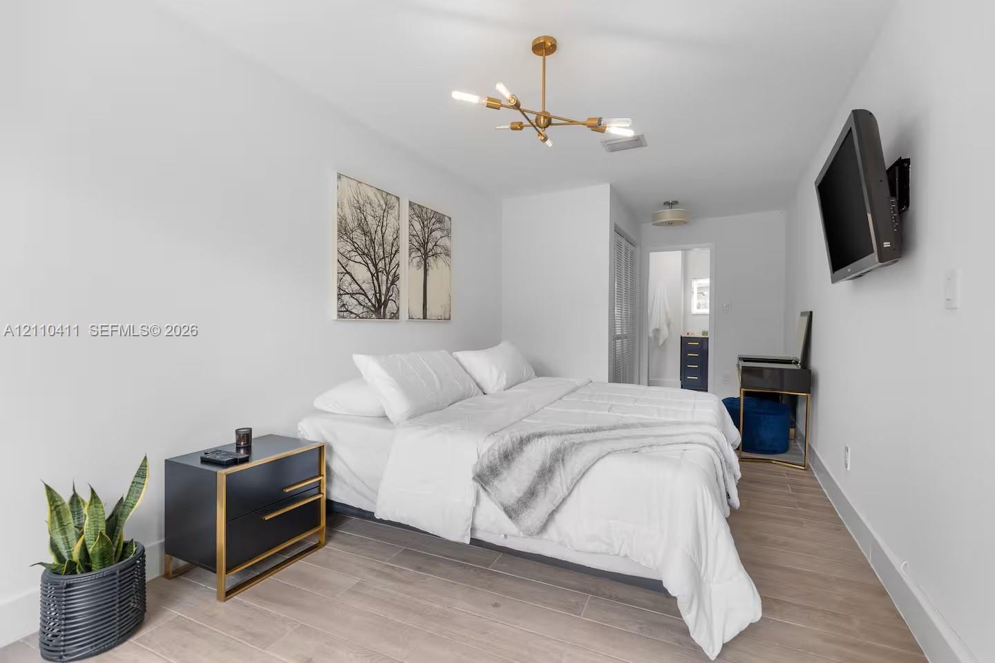Wood-finish flooring, multi-arm gold-tone chandelier, and neutral wall palette