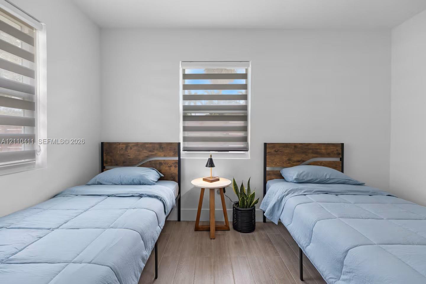 Neutral-toned walls, wood-finish flooring, and dual windows equipped with horizontal-striped roller shades