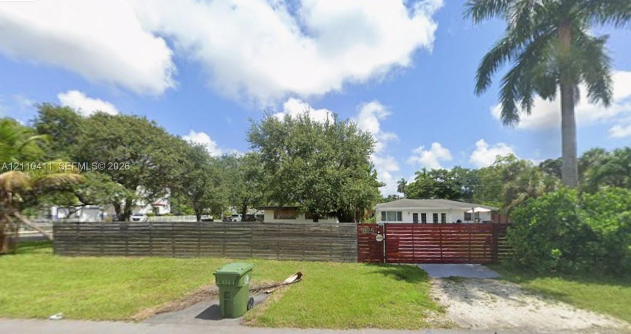 Single-story residence featuring a horizontal wood-slat privacy fence, gated entry, and mature perimeter landscaping