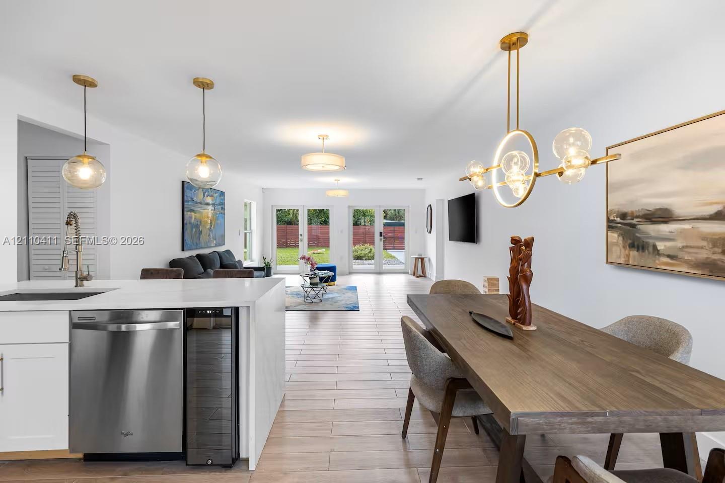 Kitchen featuring quartz countertops, stainless steel dishwasher, and built-in wine refrigerator, complemented by wood-finish flooring and designer pendant lighting