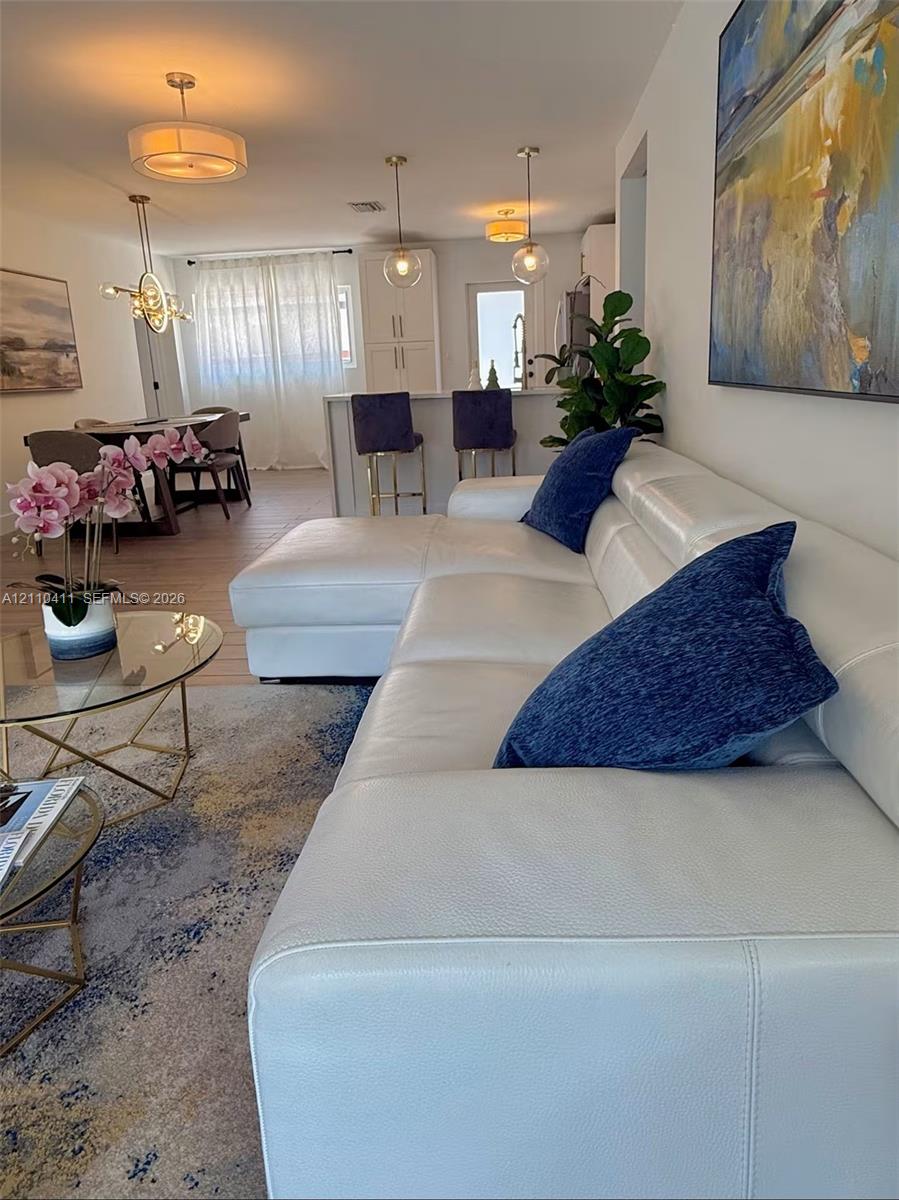 Open-concept interior featuring wood-finish flooring, multi-pendant lighting, and a kitchen island with stone countertop