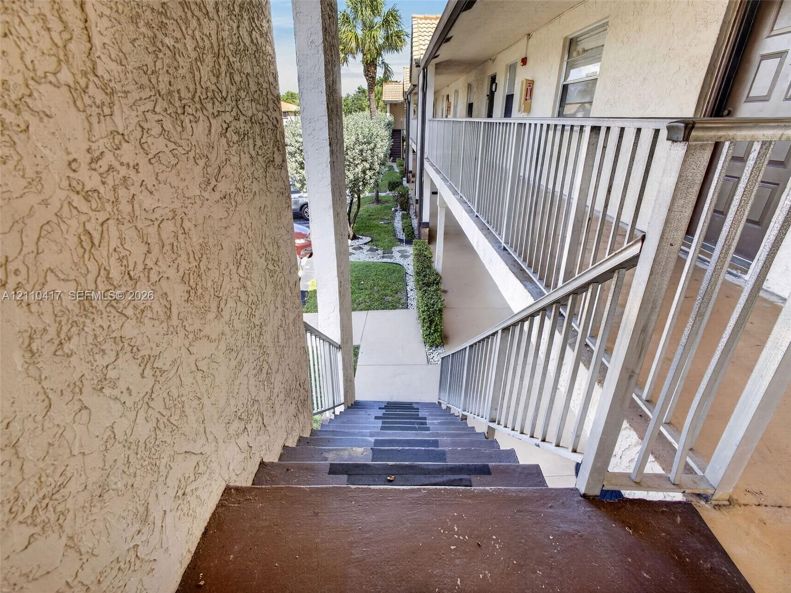 Stucco exterior staircase featuring metal railings and concrete walkway