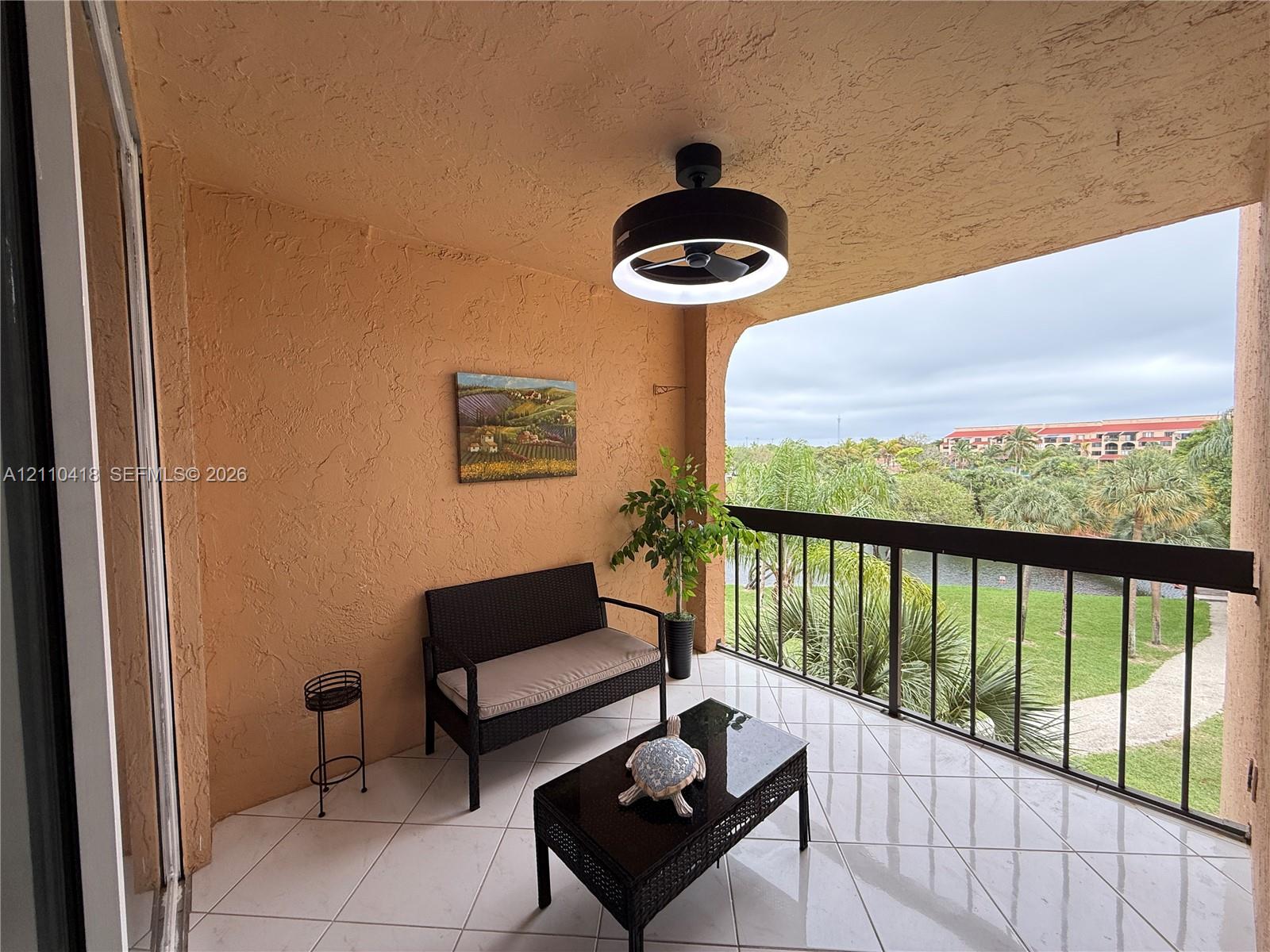 Covered balcony featuring tile flooring, textured wall finishes, and a contemporary circular LED ceiling fan with integrated lighting