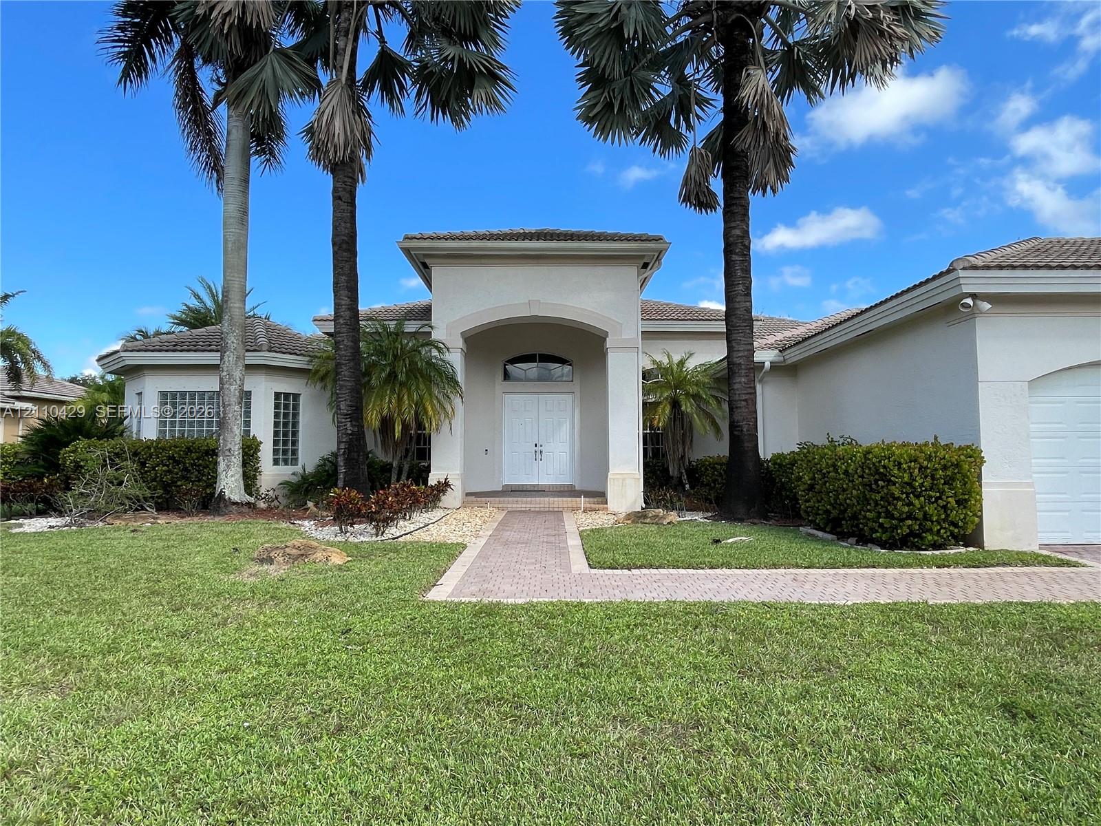 Stucco exterior featuring an arched entryway, double-door entrance, glass block windows, and a paver walkway