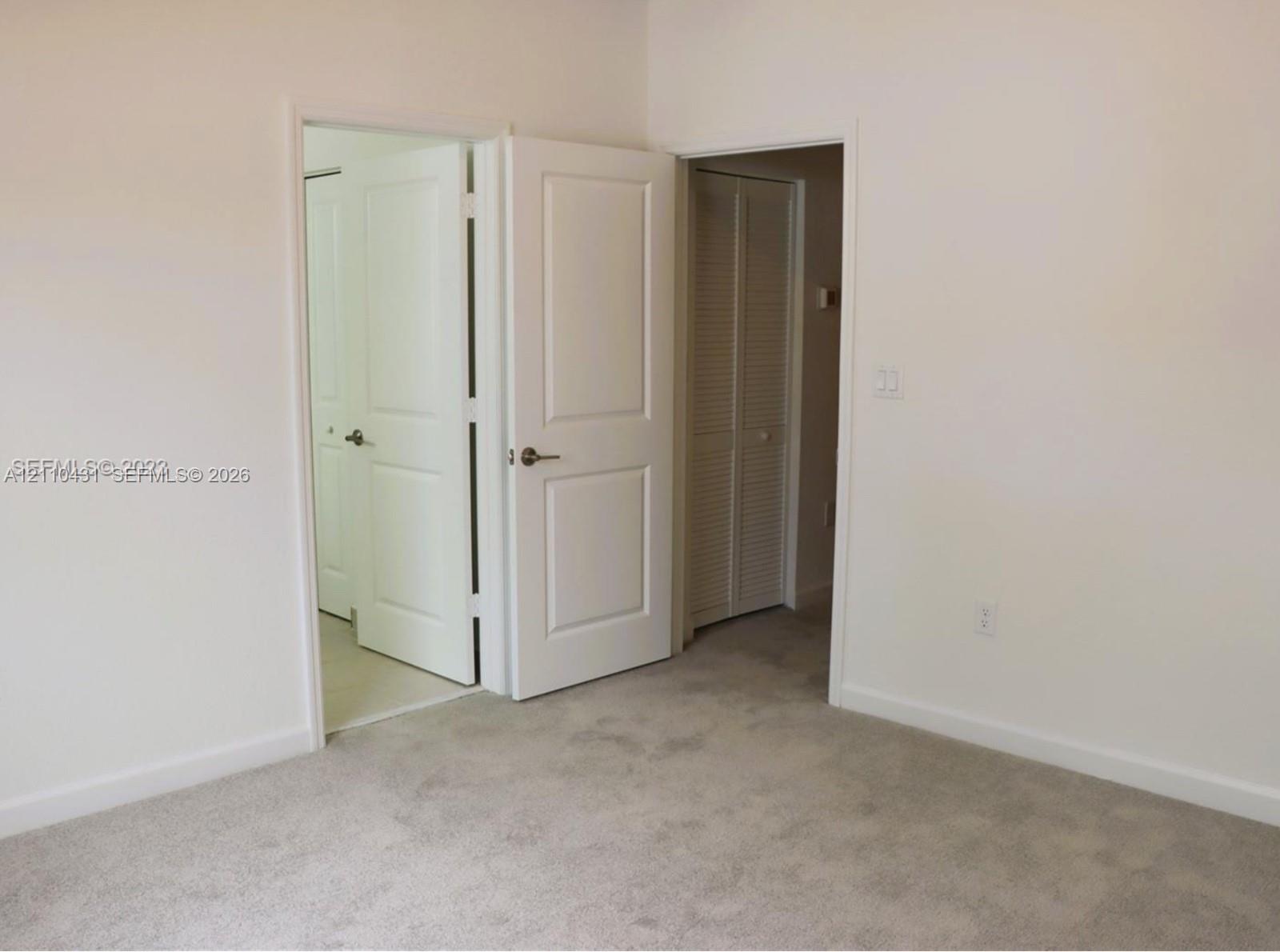 Neutral-toned wall-to-wall carpeting, two-panel interior doors with brushed nickel hardware, and louvered bi-fold closet doors