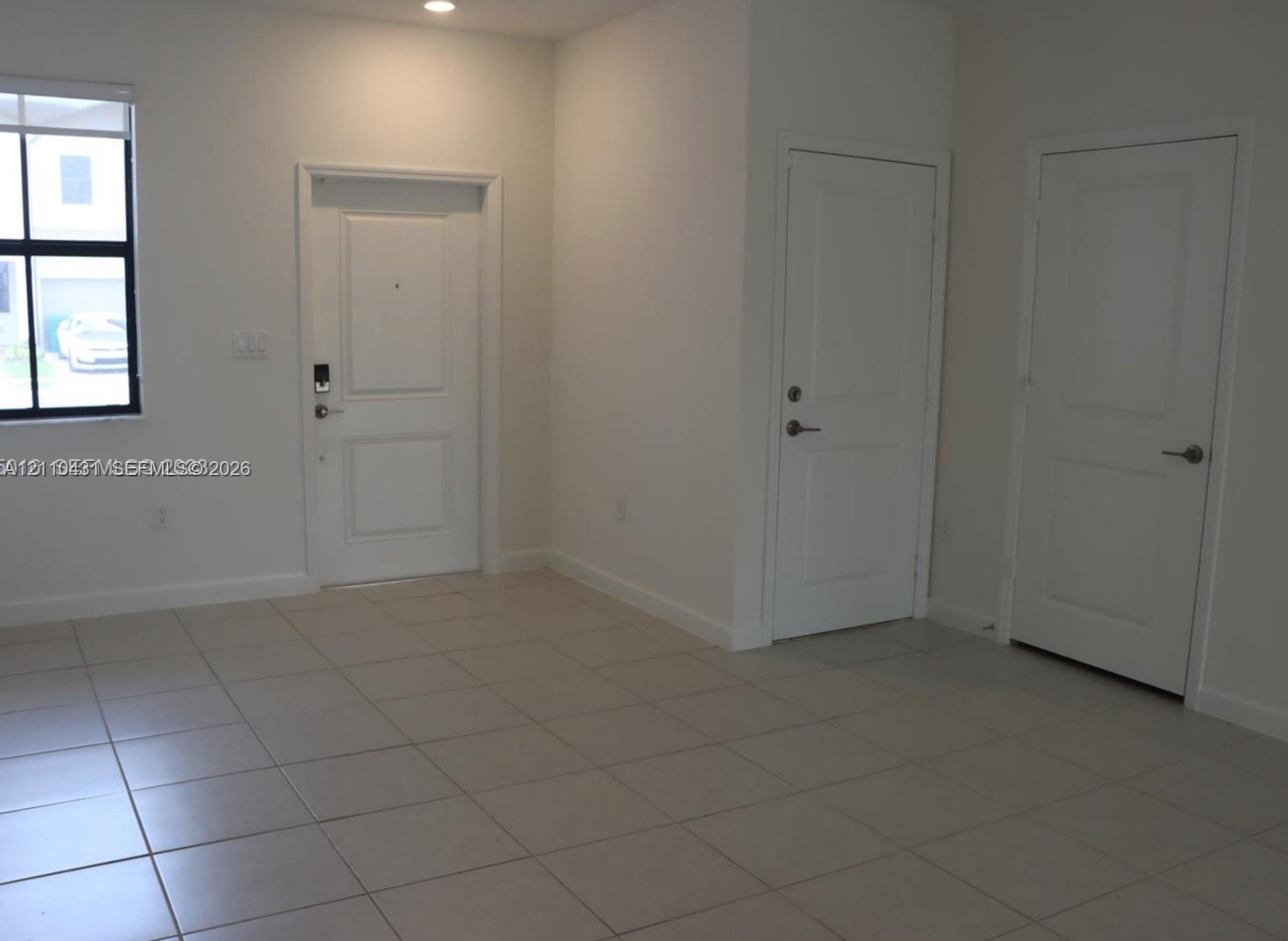 Neutral-toned tile flooring, recessed ceiling lighting, and three panel-style interior doors