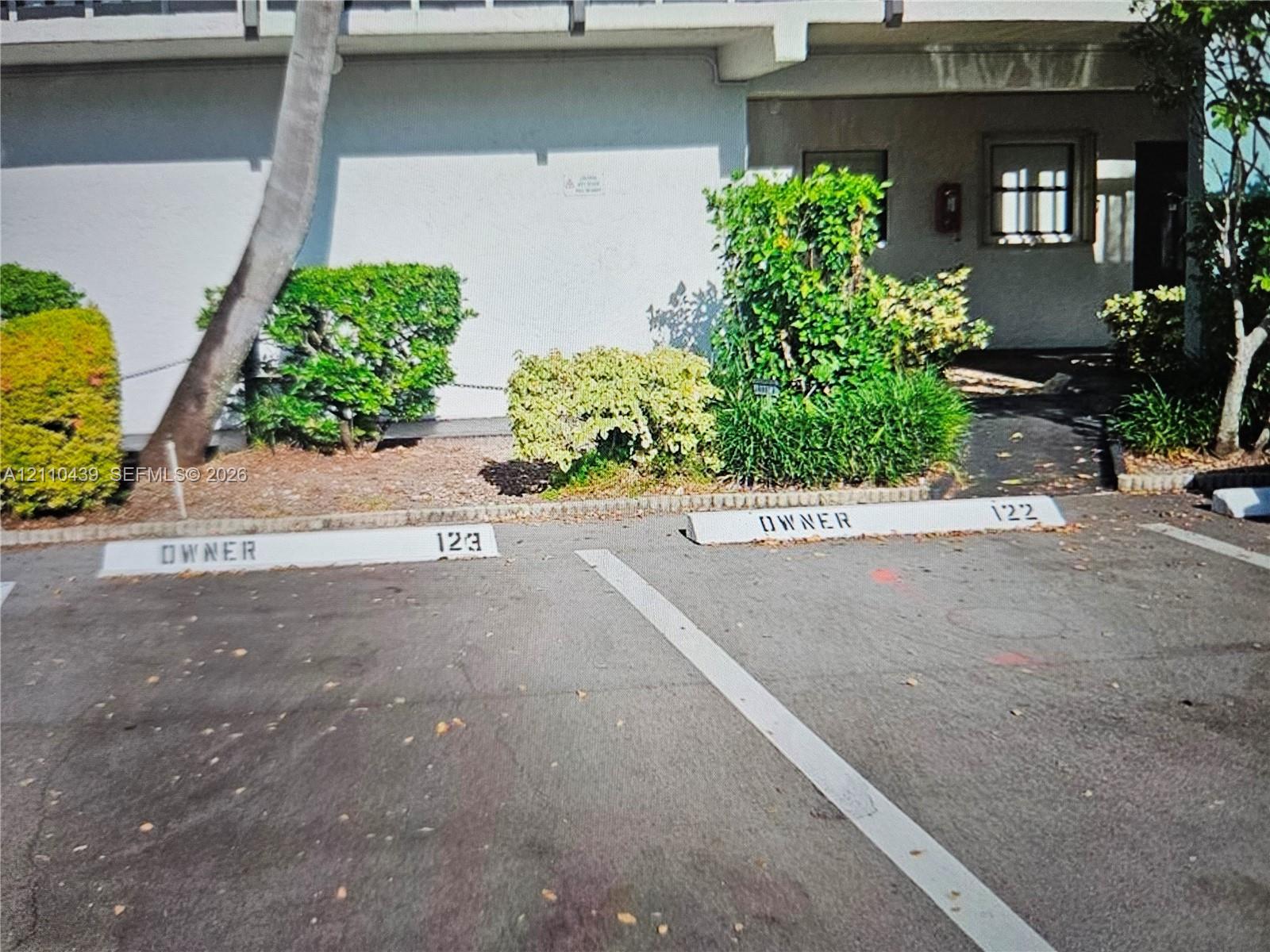 Designated parking stall marked, framed by mature landscaping and established shrubs