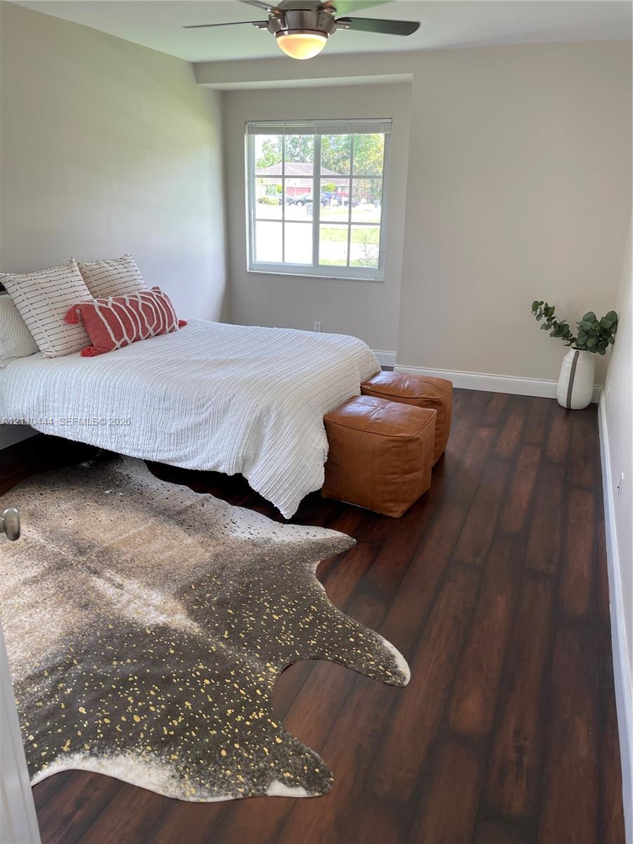 Wood-finish flooring, neutral wall tones, multi-pane window, and a ceiling-mounted light fixture with a fan