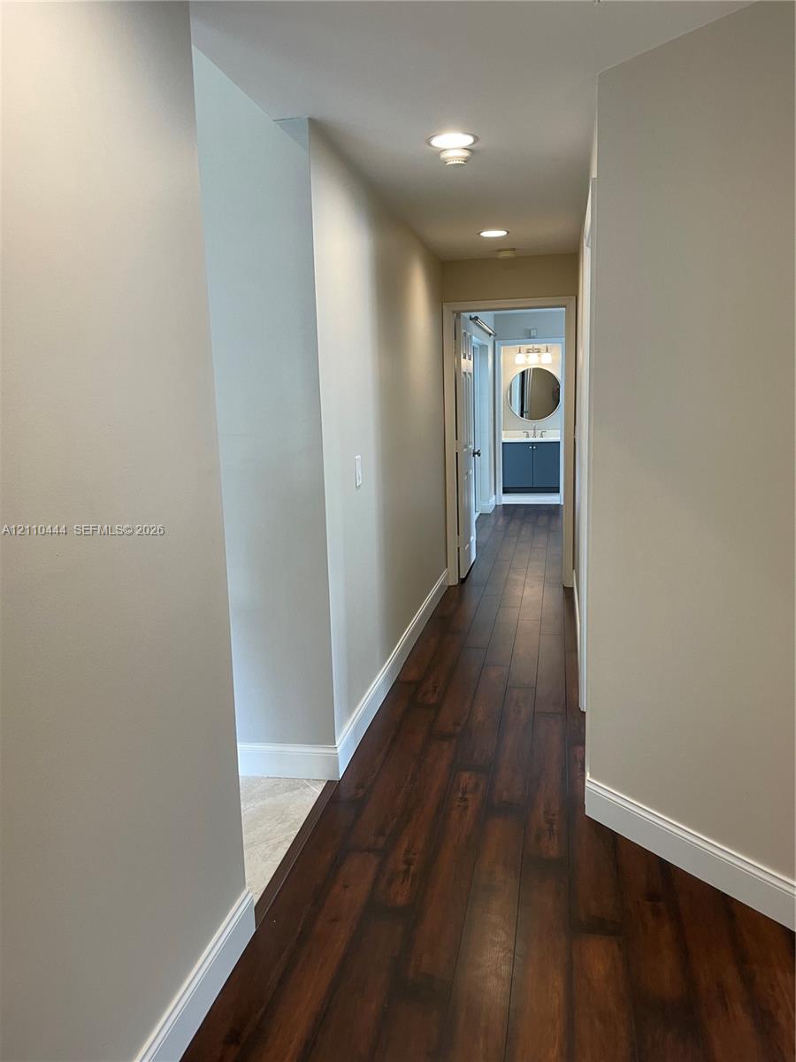 Hallway featuring wood-finish flooring, recessed lighting, and neutral wall paint