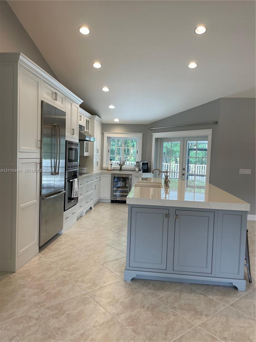 Kitchen featuring white cabinetry, center island with stone countertop, stainless steel appliances, recessed lighting, and tile flooring Kitchen featuring white cabinetry, center island with stone countertop, stainless steel appliances, recessed lighting, and tile flooring