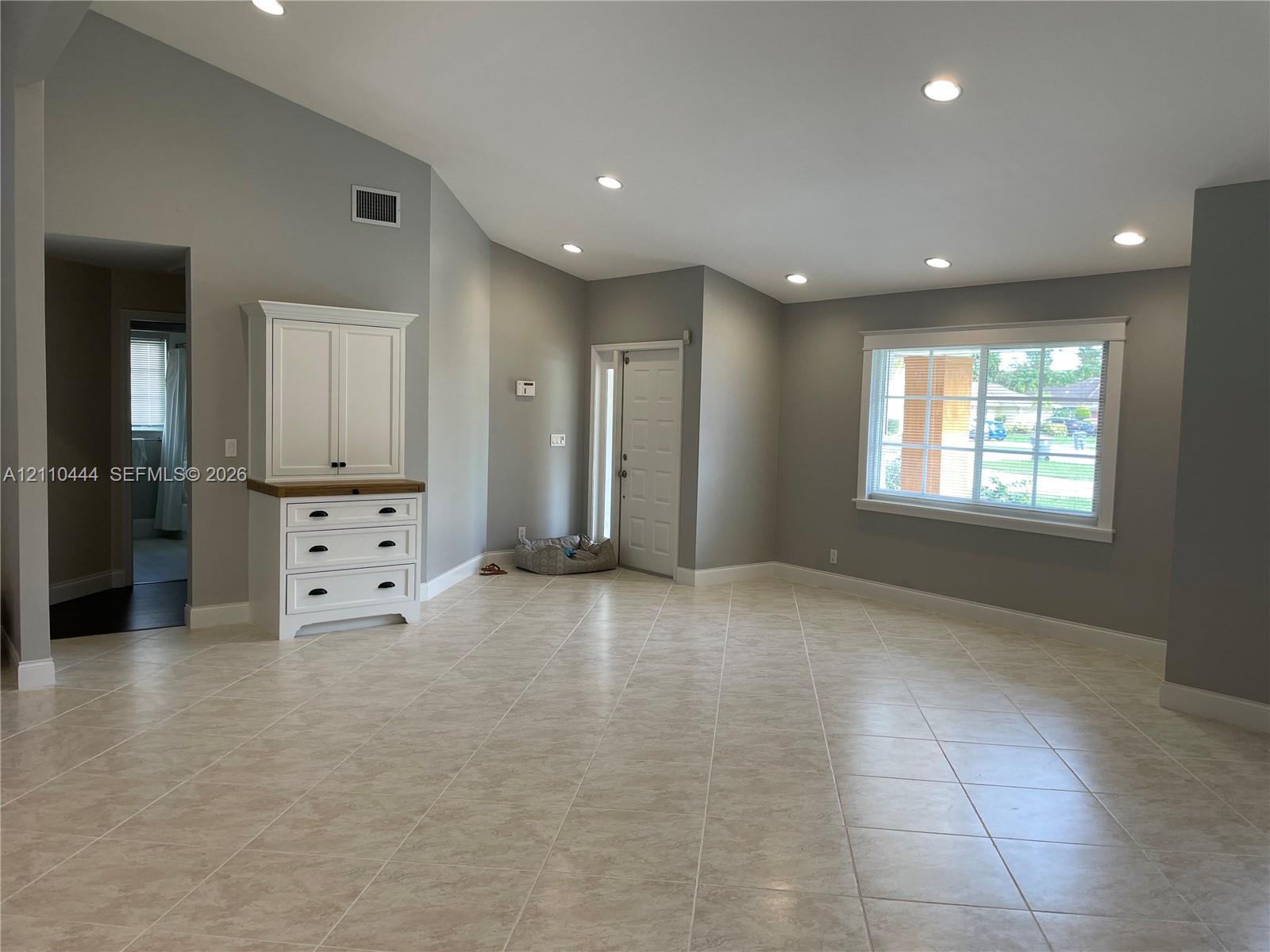 Vaulted ceilings featuring recessed lighting, large-format tile flooring, built-in cabinetry with a wood-tone surface, and a multi-pane window Vaulted ceilings featuring recessed lighting, large-format tile flooring, built-in cabinetry with a wood-tone surface, and a multi-pane window