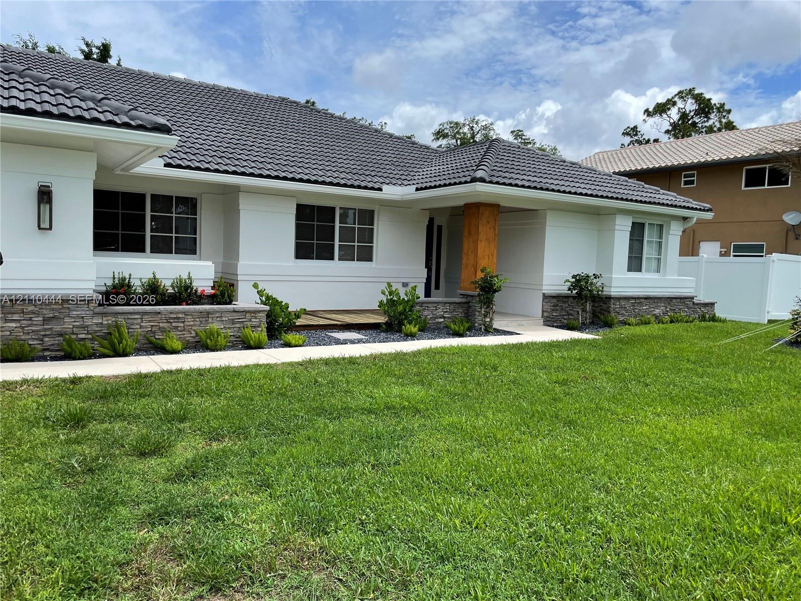 Stucco exterior featuring stacked stone accents, tile roofing, a wood-finish column, and custom grid windows
