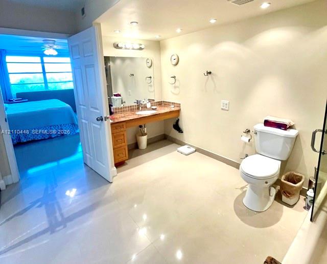 Bathroom featuring a natural stone-topped vanity with built-in cabinetry, polished tile flooring, recessed ceiling lighting, and a wall-to-wall mirror